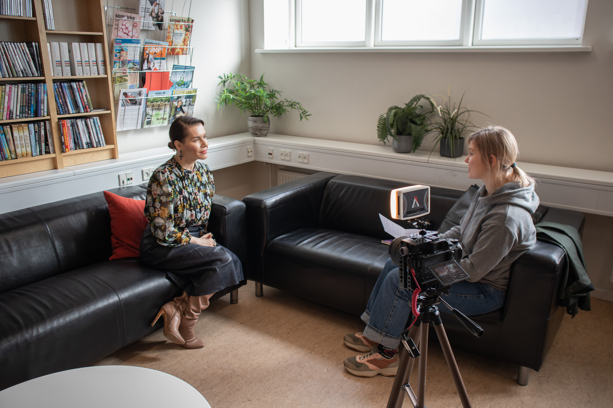 Kvinde sidder ved en sofa og bliver interviewet